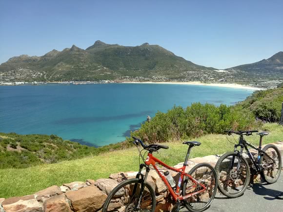 Zwei Fahrräder, die auf einer Ziegelmauer ruhen, mit dem Meer und den Bergen im Hintergrund