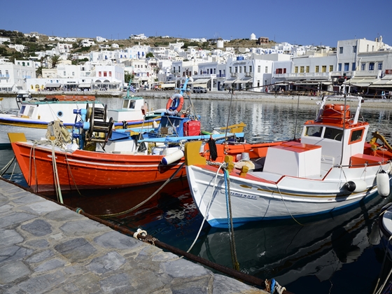 Three small fishing boats in the harbour with white buildings of the town in the background