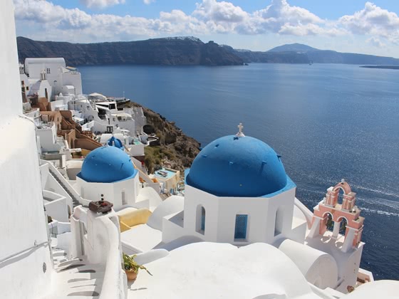 Blue domed roof churches on the cliffs of Santorini with view to sea