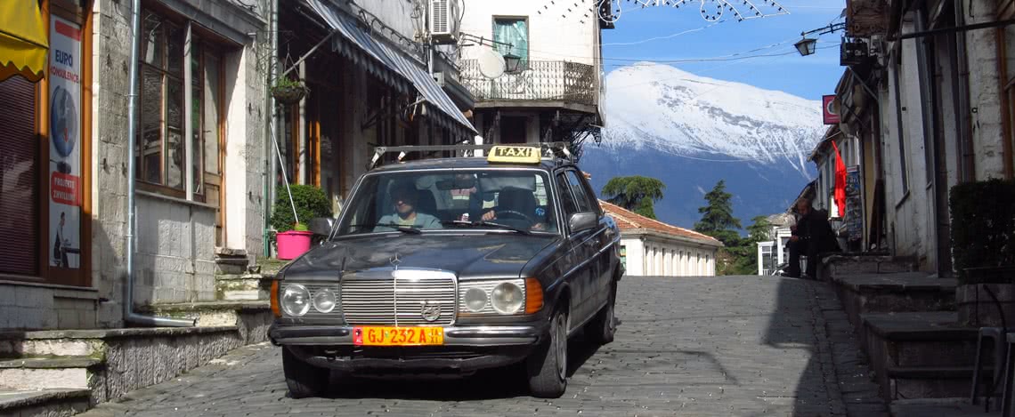 Taxi in einer Gasse mit Blick auf einen schneebedeckten Berg im Hintergrund