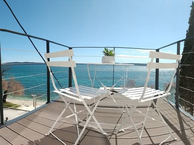 Balcony with table and chairs and view out to sea