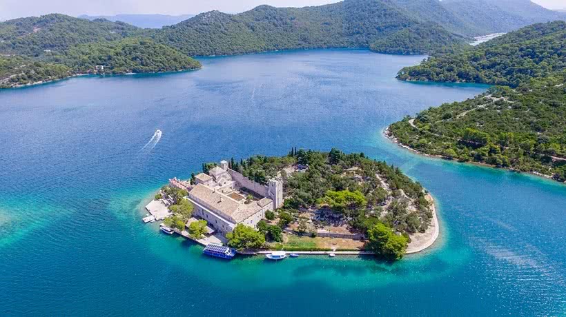 Aerial view of Mljet island: a small chain of islands surround a little lake. In the lake is an old building situated on a peninsula.