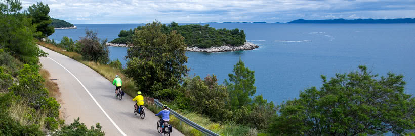 Three cyclists biking along a coastal road